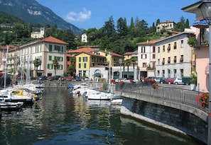 Waterfront buildings stand along the tranquil shore, connected by a stone bridge.