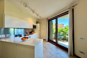 A modern kitchen with a large island, built-in appliances, and a view to a balcony.