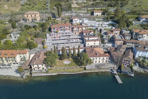 An aerial view of a coastal town with buildings along the waterfront, a central circular plaza, and a dock extending into the water.