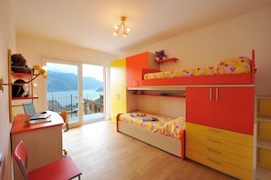 A room with a bunk bed, a desk with a laptop, and a chair.