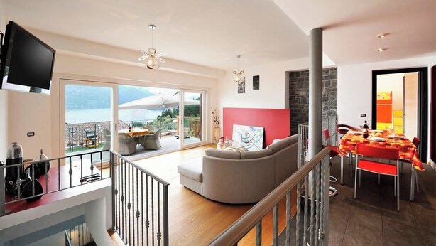 A spacious living area with a balcony, a dining table, and a sofa. - Villa Bianca - Grande (Menaggio)