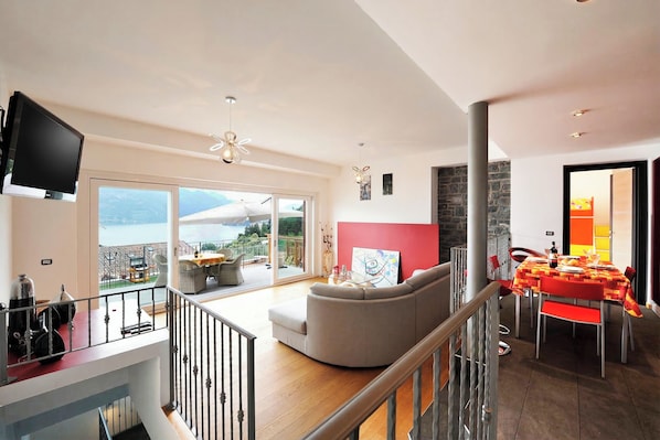 A spacious living area with a balcony, a dining table, and a sofa. - Villa Bianca - Grande (Menaggio)
