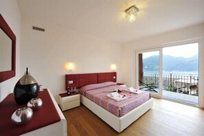 A bedroom with a bed, bedside tables, and a view of the sea. - Villa Bianca - Grande (Menaggio)