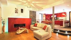 A modern living room with a fireplace, a sofa, and a kitchen in the background. - Villa Bianca - Grande (Menaggio)