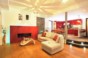 Una sala de estar moderna con chimenea, un sofá y una cocina al fondo.