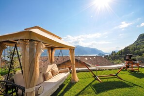 A hammock, a sofa, and a pergola in a sunny outdoor setting with mountains in the background. - Villa Bianca - Grande (Menaggio)