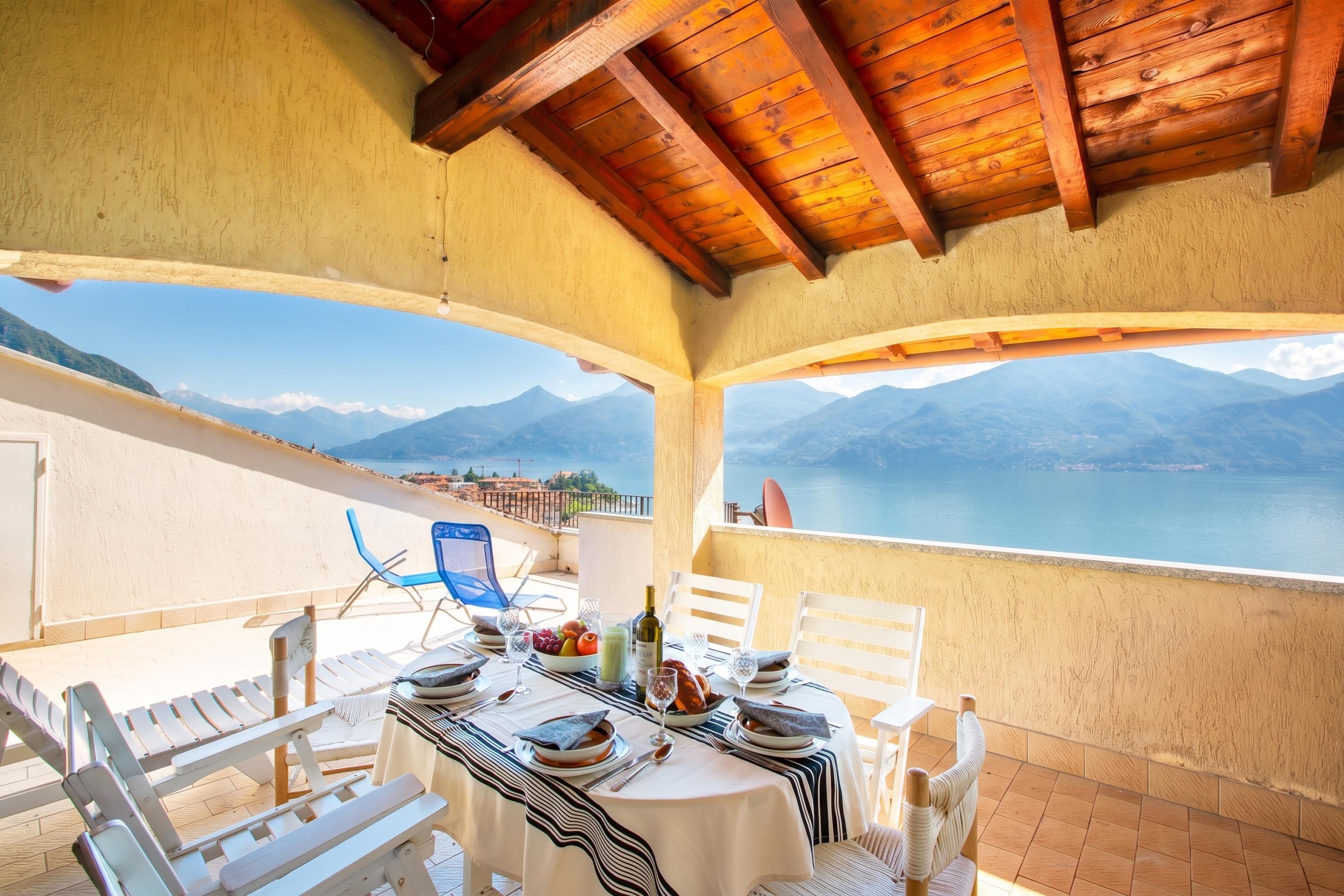 A dining area with a table set for two, overlooking a scenic mountain and lake view.