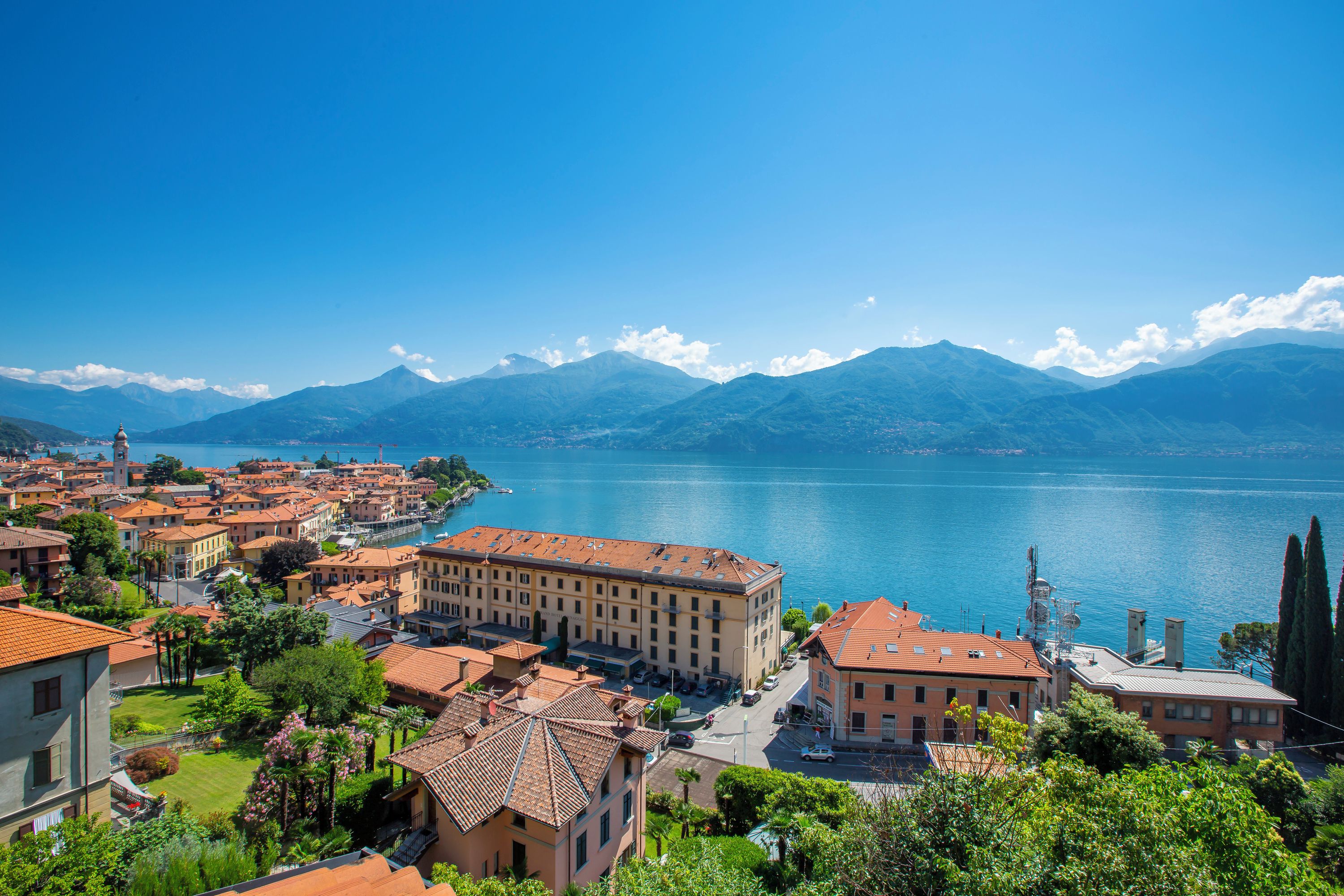 A coastal town with buildings along the waterfront, a clear view of the lake, and mountains in the background.