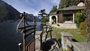 A lakeside building with a stone entrance and a view of the lake and mountains. - Villa Chez Nous (Pognana Lario)