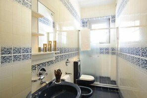 Ein Badezimmer mit einem schwarzen Waschbecken, einer Toilette und einer Duschkabine.