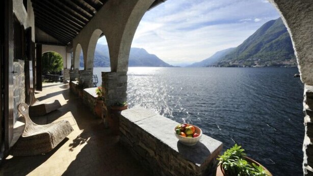A covered outdoor area with stone arches overlooking a body of water and mountains. - Villa Chez Nous (Pognana Lario)
