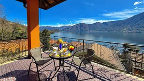 A balcony with a table set for breakfast, overlooking a lake and mountains. - Isola Vista - Terrazzo (Sala Comacina)