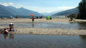 Una playa junto al lago con gente relajándose y tiendas de campaña instaladas.