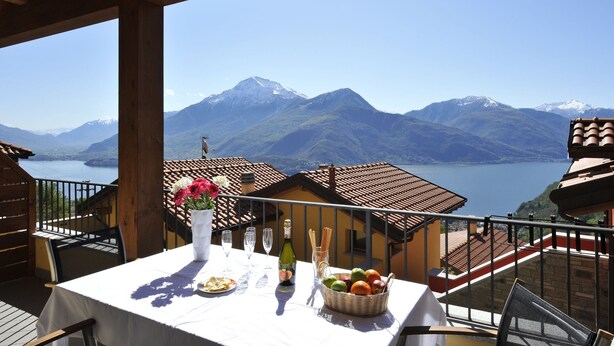 A terrace with a table set for dining, overlooking a mountainous landscape and a lake. - Borgo La Sorgente - Magnolia (Gravedona)
