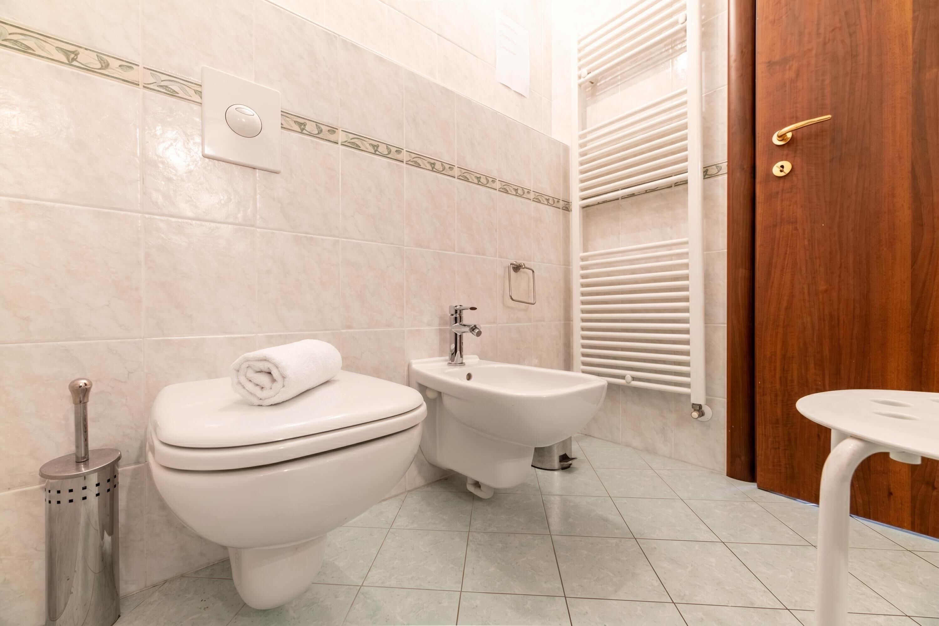 A bathroom with a toilet, bidet, and a small table.