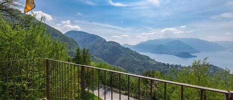Ein Balkon mit Blick auf eine kurvenreiche Straße, üppiges Grün und entfernte Berge.