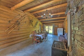 Ein rustikales Blockhaus-Interieur mit Esstisch, Stühlen, einer Kandelaber, einer Steinwand und einem Kamin.