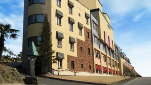 Ein mehrstöckiges Hotel mit einer gebogenen Ecke, zahlreichen Fenstern und einer Fassade aus Backstein und Putz.