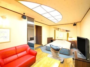 A hotel room with a red sofa, a bed with a headboard, a TV, and a skylight. - Hotel Com - Adults Only (Nagoya)