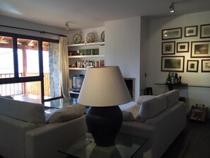 A living room with a sofa, a glass coffee table, a lamp, a fireplace, and a bookshelf with various items. - Duplex 3 Bed Rustic Style, Fireplace, Terrace & Cadí Views (Guils de Cerdanya)