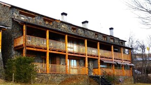 A multi-story stone building with wooden balconies and a staircase leading to the entrance. - Duplex 3 Bed Rustic Style, Fireplace, Terrace & Cadí Views (Guils de Cerdanya)