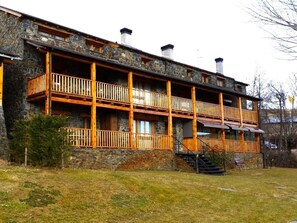 A multi-story stone building with wooden balconies and a staircase leading to the entrance.