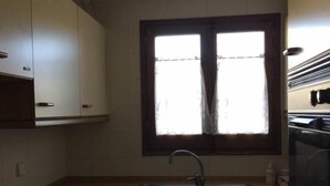 A kitchen with a window, sink, cabinets, and a stove. - Duplex 3 Bed Rustic Style, Fireplace, Terrace & Cadí Views (Guils de Cerdanya)
