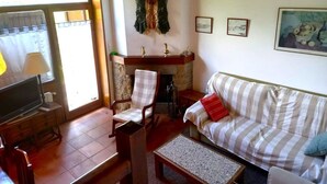 A cozy living room with a fireplace, a sofa, a TV, and a dining area. - House 3 rooms Fireplace, Garden & Dryer (Guils de Cerdanya)