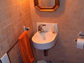 Une salle de bain avec un lavabo blanc, un miroir et un porte-serviettes.