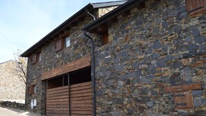 A stone building with a wooden garage door and a metal gutter. - House 3 rooms Fireplace, Garden & Dryer (Guils de Cerdanya)