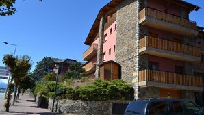 Un immeuble à plusieurs étages, doté de balcons en pierre et en bois, d’une façade en pierre et surplombant un ciel dégagé.