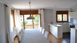 Une cuisine spacieuse avec un coin repas, un plancher en bois et une vue sur la verdure environnante.
