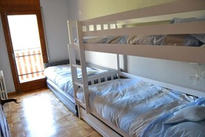 A bunk bed with a ladder, a window with blinds, and a radiator.