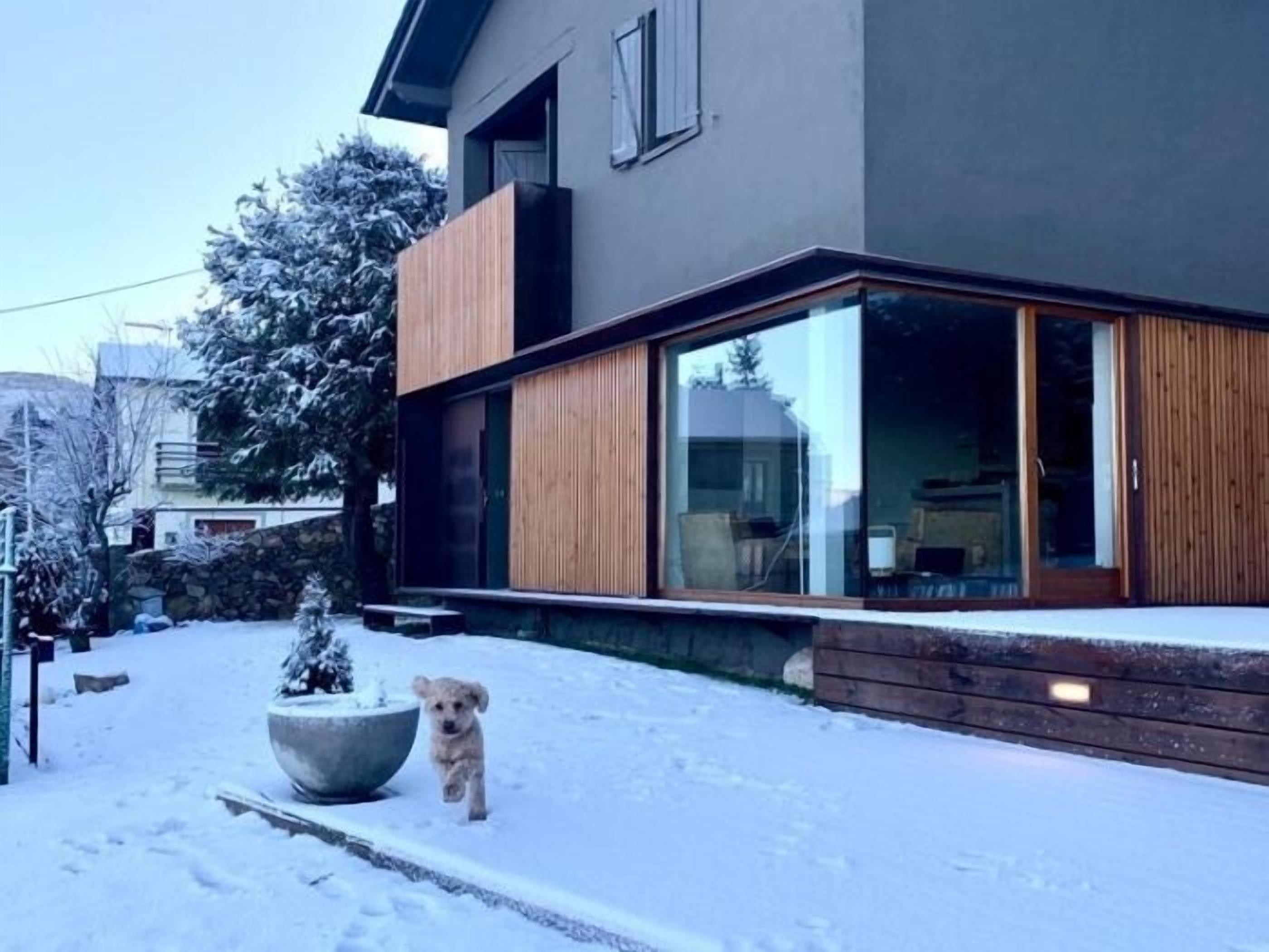 Et moderne hus med store vinduer og en træterrasse.