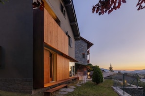 A modern two-story house with a stone facade, wooden slats on the exterior, a wooden deck, and a view of the mountains. - Design Townhouse 3 Bed, Fireplace, Garden & Wi-Fi (Alp)