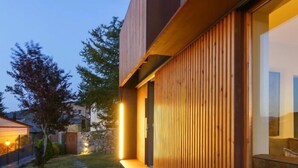 A modern building with a wooden exterior, a bench, and a pathway leading to the entrance.