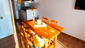 Una cocina compacta con una mesa y sillas, un microondas y un refrigerador pequeño.