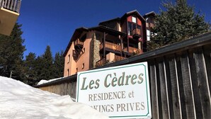 Señal para 'Les Cèdres Residence and Priveks', con una valla de madera y nieve al frente.