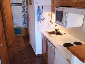 A kitchen with a sink, stove, and microwave.