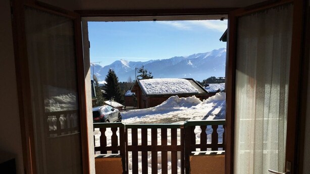 Un balcón con vistas a montañas nevadas y una valla de madera.