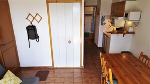 Un espacio habitable compacto con una mesa de comedor de madera, sillas, un sofá y una zona de cocina con microondas y tostadora.