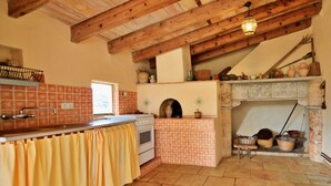 Una cocina rústica con techo de madera, salpicadero de azulejos, estufa y chimenea.