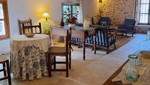 A rustic room with a round table, chairs, a sofa, and a stone wall. - Hort Den Gelos (Pollensa / Pollença)