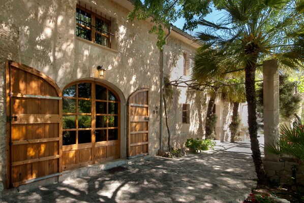 A building with arched wooden doors, a stone facade, and a palm tree.