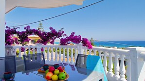 A table with a fruit bowl, two cups, and a blue towel on a balcony overlooking the sea. - Rouladina Apt 1 (Stalos)