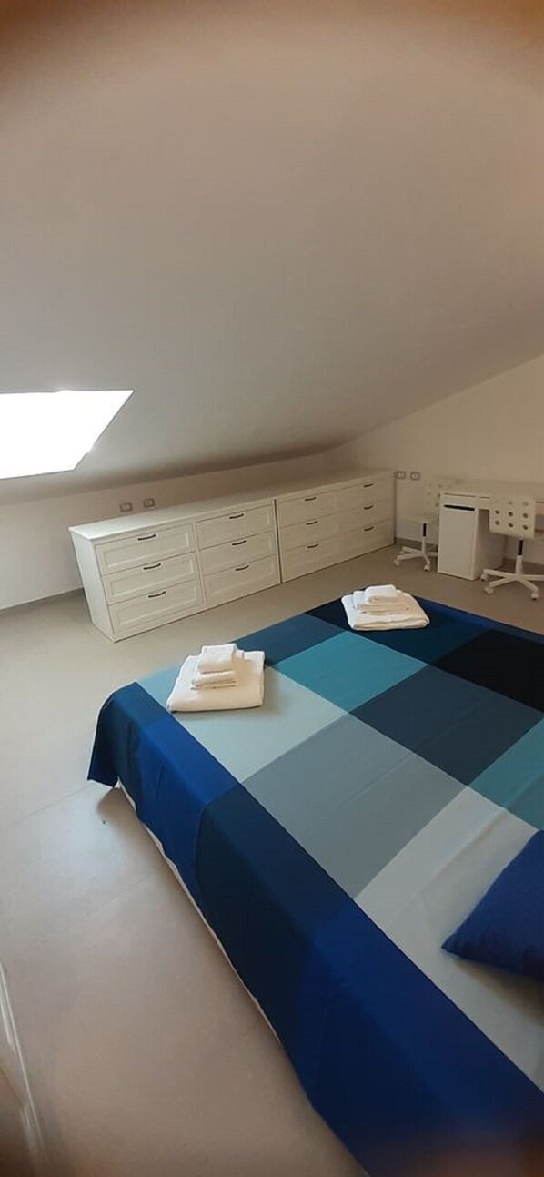 A bedroom with a large bed, a desk, and a dresser.