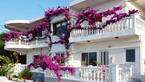 A two-story building with balconies covered in purple bougainvillea. - Rouladina Apt 2 (Stalos)