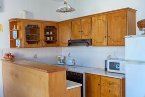 Une cuisine avec des meubles de rangement en bois, un plan de travail blanc, une machine à café, un grille-pain et un four à micro-ondes.