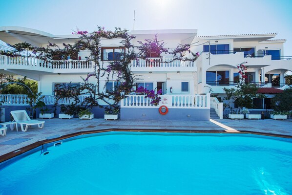 A modern hotel with a swimming pool, balconies, and outdoor seating. - Rouladina Apt 3 (Stalos)