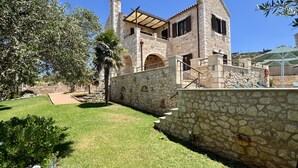 A stone building with a covered patio and a stone staircase leading to the entrance. - Villa Afrati (Plaka)
